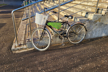 Obraz premium A bicycle with a basket stands near the porch with a railing.