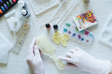 Female hands in gloves hold a mold for making a comb from epoxy resin