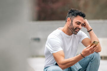 Obraz premium attractive young adult man with beard outdoors chatting smiling with mobile phone