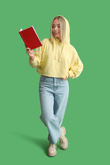 Beautiful young happy woman with book on green background