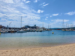 Kreuzfahrtschiff und andere Segelboote und Yachten im Hafen von Palamós vom Strand aus gesehen an...