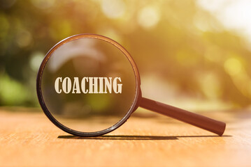 A magnifying glass highlights the word Coaching on a warm, sunny day.