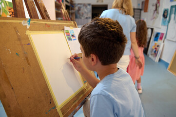 Children enjoying an art class, drawing and painting with their teacher in a creative workshop