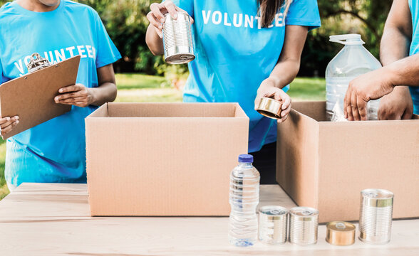 Team of volunteers work collecting goods and food for community service at park city. Donations and charity project concept