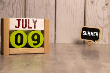 July 9 calendar date text on wooden blocks with blurred background park.
