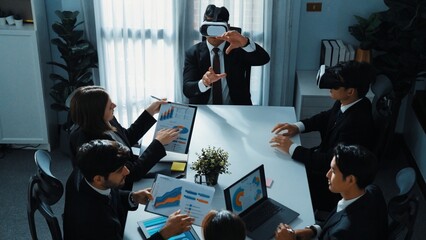 Top view of manager working on laptop and sending data analysis to business people by using VR glass headset while diverse team planning marketing strategy and looking at financial graph. Directorate.