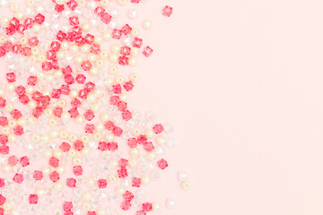 Different acrylic beads scattered on a pink background with copy space.