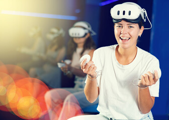 Girl gamer with virtual reality glasses on her forehead expresses enthusiastic emotions from...