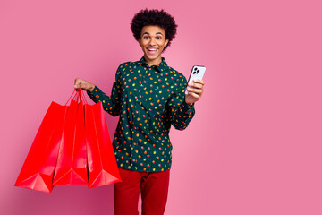 Photo of cheerful positive guy with wavy hairstyle dressed print shirt hold shopping bags...