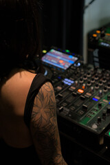 DJ with Tattoos Operating a Mixing Board in a Nightclub - High-End Audio Equipment in Action