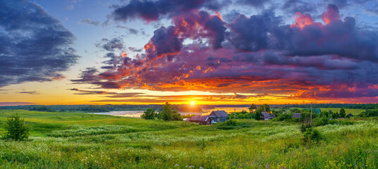 Panoramic view on dramatic sunset over lake and old village in countryside © sborisov