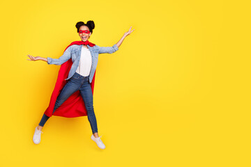 Obraz premium Full size photo of nice young girl jump empty space superhero costume isolated on yellow color background