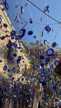 Hanging Blue evil eye amulets, souvenir, traditional Turkish decoration in the street, the eye of Fatima , swaying in the wind, vertical video, 4K
