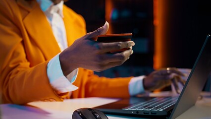 African american girl doing online shopping session at home, typing debit card numbers to finish...