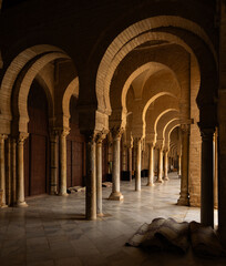 Long narrow passages under arches of temple, courtyard of great Mosque of Uqba in Tunisia. Muslim architecture, ancient religious buildings that have survived to present day © JackF