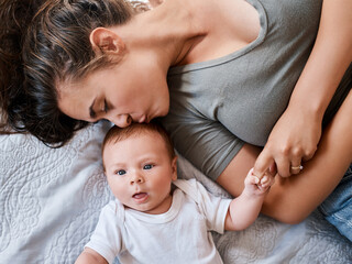 Kiss, mother and baby in bed at home for relax, rest and bonding together as family. Happy people, mom and boy infant in bedroom for embrace with love, support or security as parent in apartment