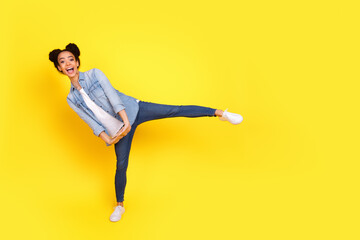 Full size photo of nice young girl dancing empty space wear denim shirt isolated on yellow color...