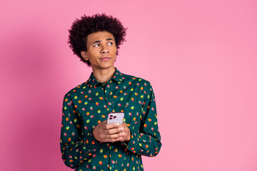 Portrait of minded guy with wavy hairstyle dressed print shirt hold smartphone look at offer empty...