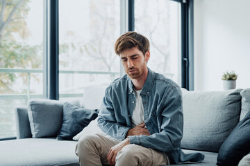 Sick young man in pain holding belly stomach feeling hurt abdomen ache gastritis pancreatitis symptoms or diarrhea, upset adult suffering from indigestion flatulence abdominal problem concept.