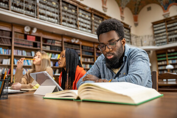Curly-haired bearded african american man in the library looking thoughtful