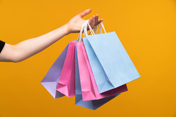 Studio image of female hand holding a bunch of pastel colored papaer shopping bags isolated over...