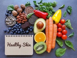 Foods for healthy glowing skin. Assortment of various natural products high in vitamins and minerals for skin health. Diet for beautiful supple skin. Skin regeneration food concept with written text.