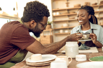 Two people working with pottery and looking involved