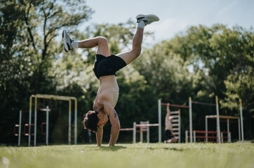 Man performing calisthenics with a handstand in an urban park. Sunny day with outdoor fitness...