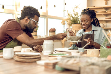Two people working with pottery and looking involved
