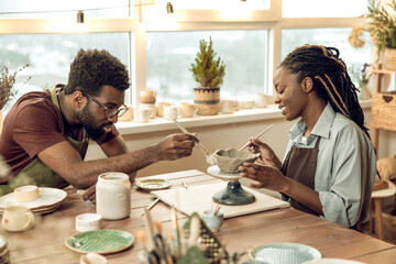 Man and woman looking focused while working with pottery