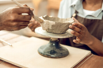 Close up of a human hand with a brush and a clay mug