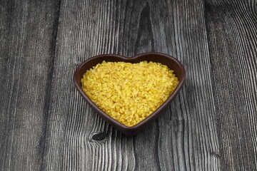 Dry bulgur wheat grains with a spoon close up