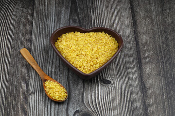 Dry bulgur wheat grains with a spoon close up