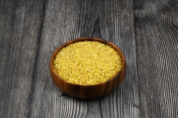 Dry bulgur wheat grains with a spoon close up