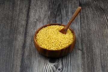 Dry bulgur wheat grains with a spoon close up
