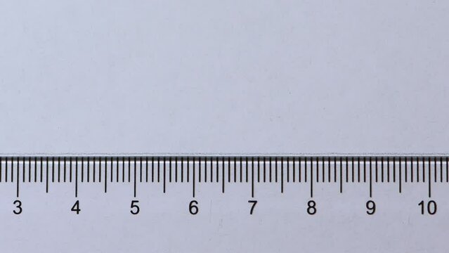 Extreme close-up pencil drawing straight line across a plastic ruler white paper copy space 