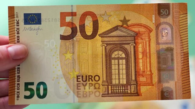 Fifty euros in hand close-up. Cash euro bill falls on euro money on a green background.Income of women in European countries. 4k footage