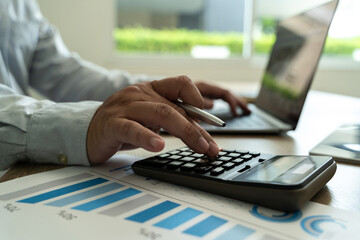 Close-up businessman using calculate finances of hands typing on a laptop keyboard in an office setting  report in office