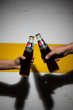 Lisbon, Portugal - 09-06-2023: Hand picking up a bottle of Pepsi Zero Sugar from a blue crate filled with similar bottles.
