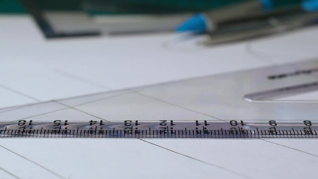 Close-up pencil drawing straight line across a plastic 60 degree set square white paper copy space