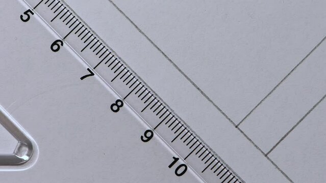 Close-up pencil drawing a 45 degree angle lines across a plastic Set Square white paper copy space 