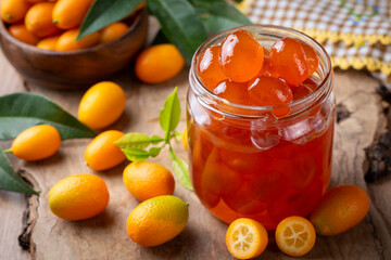 Homemade kumquat jam in jar and fresh kumquats, top view