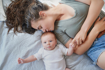 Kiss, mom and baby in bed at home for relax, rest and bonding together as family. Happy people, mother and boy infant in bedroom for embrace with love, support or security as parent in apartment