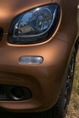 Fototapeta premium Leftist front wheel and headlight. Replicas of Russian cars. Halogen lighting at the Orange-brown car.