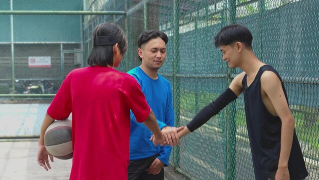 Asian Teenage Basketball Team Stacking Hands On Court Before Starting Playing Streetball Game. 