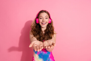 Photo of charming positive girl wear retro outfit earphones showing arms empty space isolated pink color background