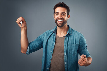 Celebrate, portrait and happy man with key in studio for real estate, property or new home owner on...