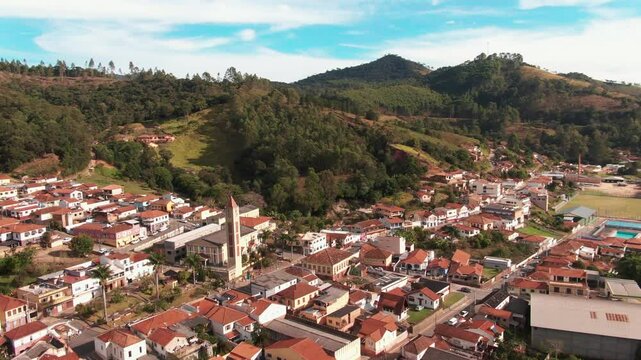 Aerial view of Delfim Moreira in Minas Gerais, Brazil, featuring a small town with clustered houses surrounded by hills and forests