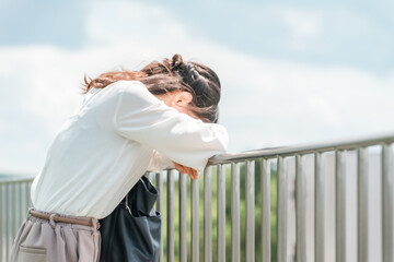 屋上で落ち込むビジネスウーマン（絶望・過労・失業・ハラスメント）
