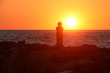 A figure silhouetted against the rising sun at a beach in Virginia